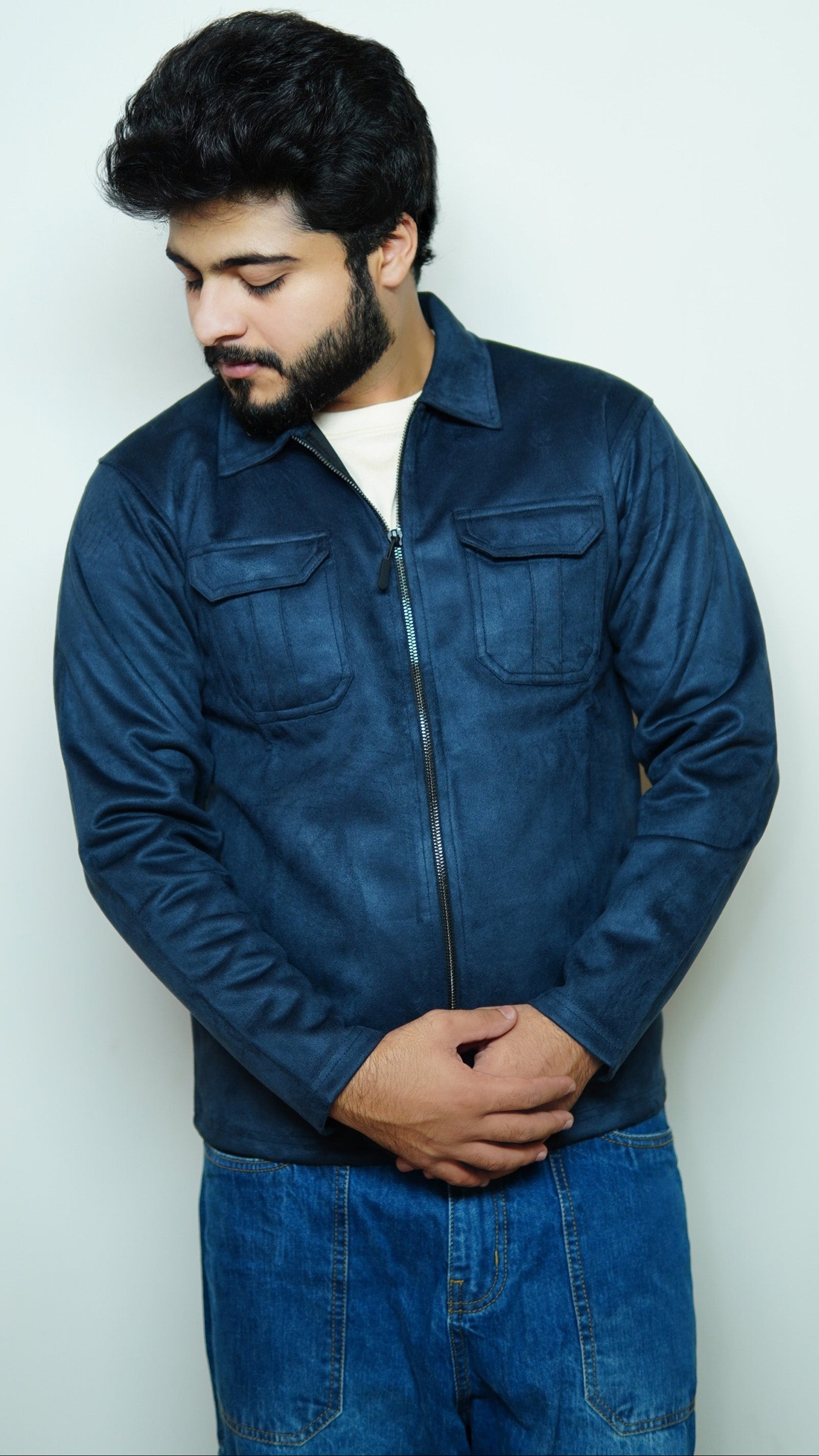 Man wearing a blue denim jacket and jeans against a white background