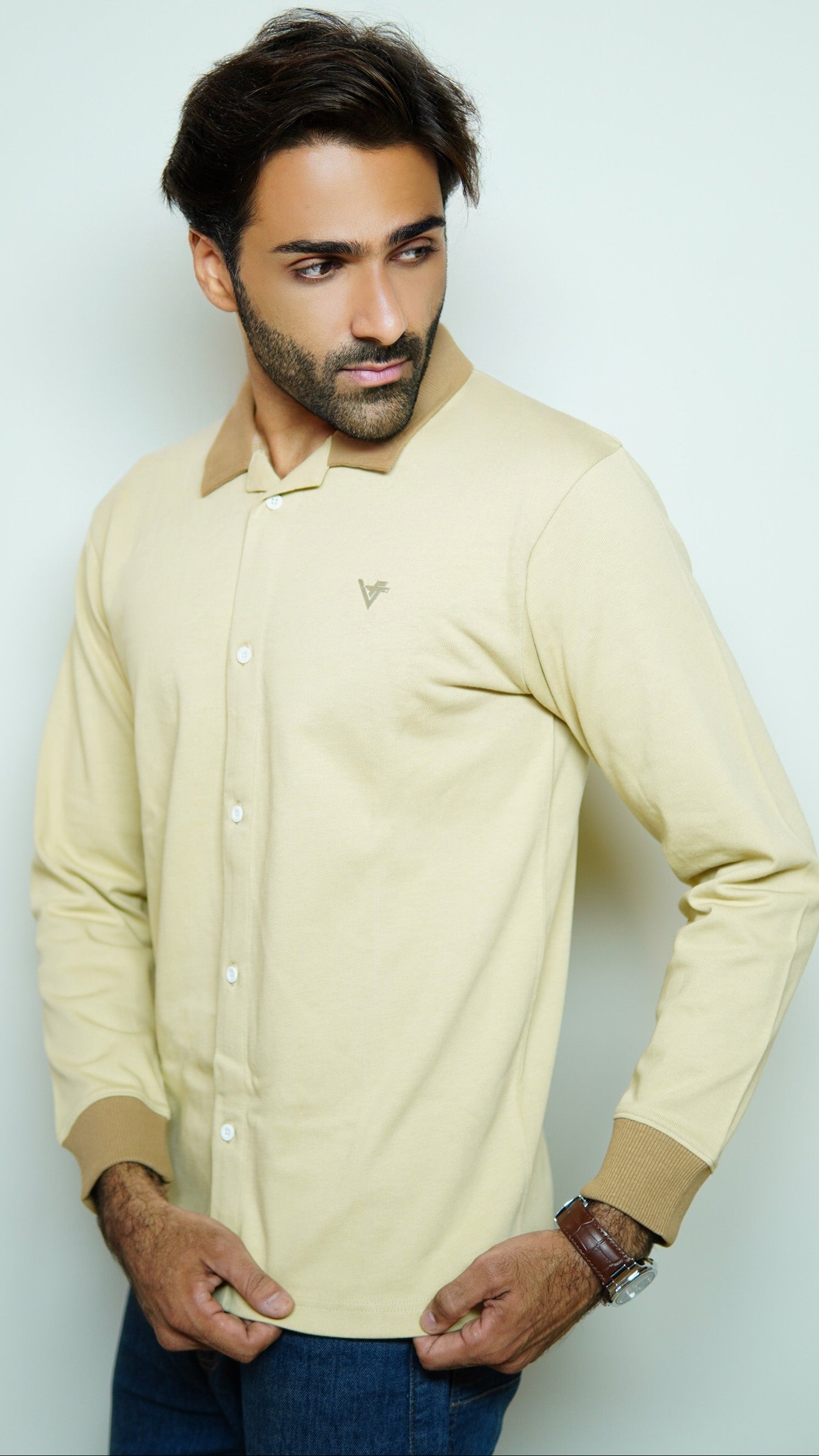 Man wearing a beige long-sleeve shirt against a light gray background
