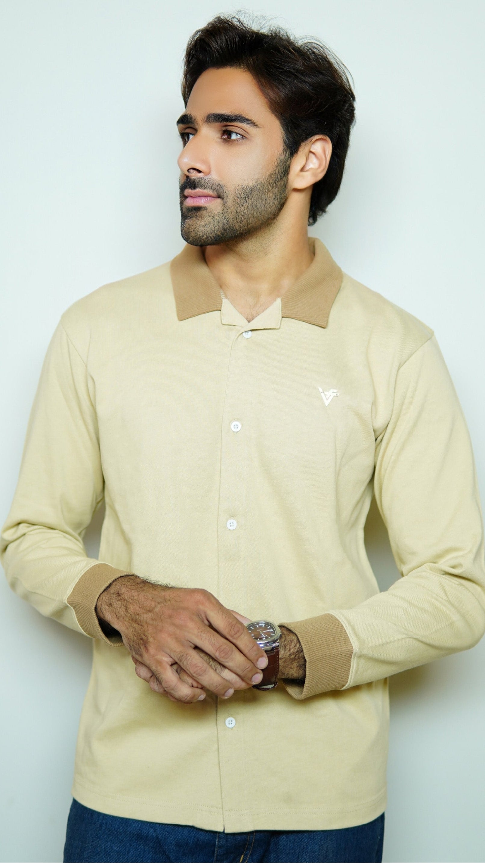 Man wearing a beige shirt with a collar against a light gray background