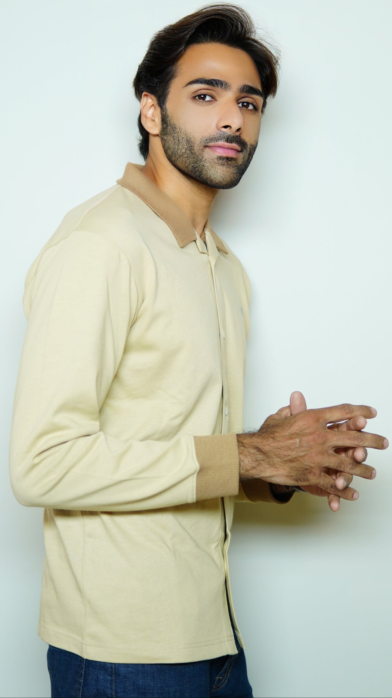 Man wearing a beige sweater against a light gray background