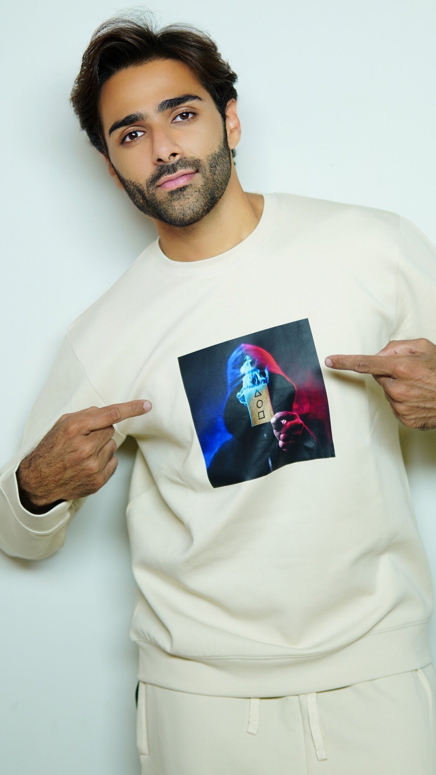 Man pointing to a photo on his chest against a plain background