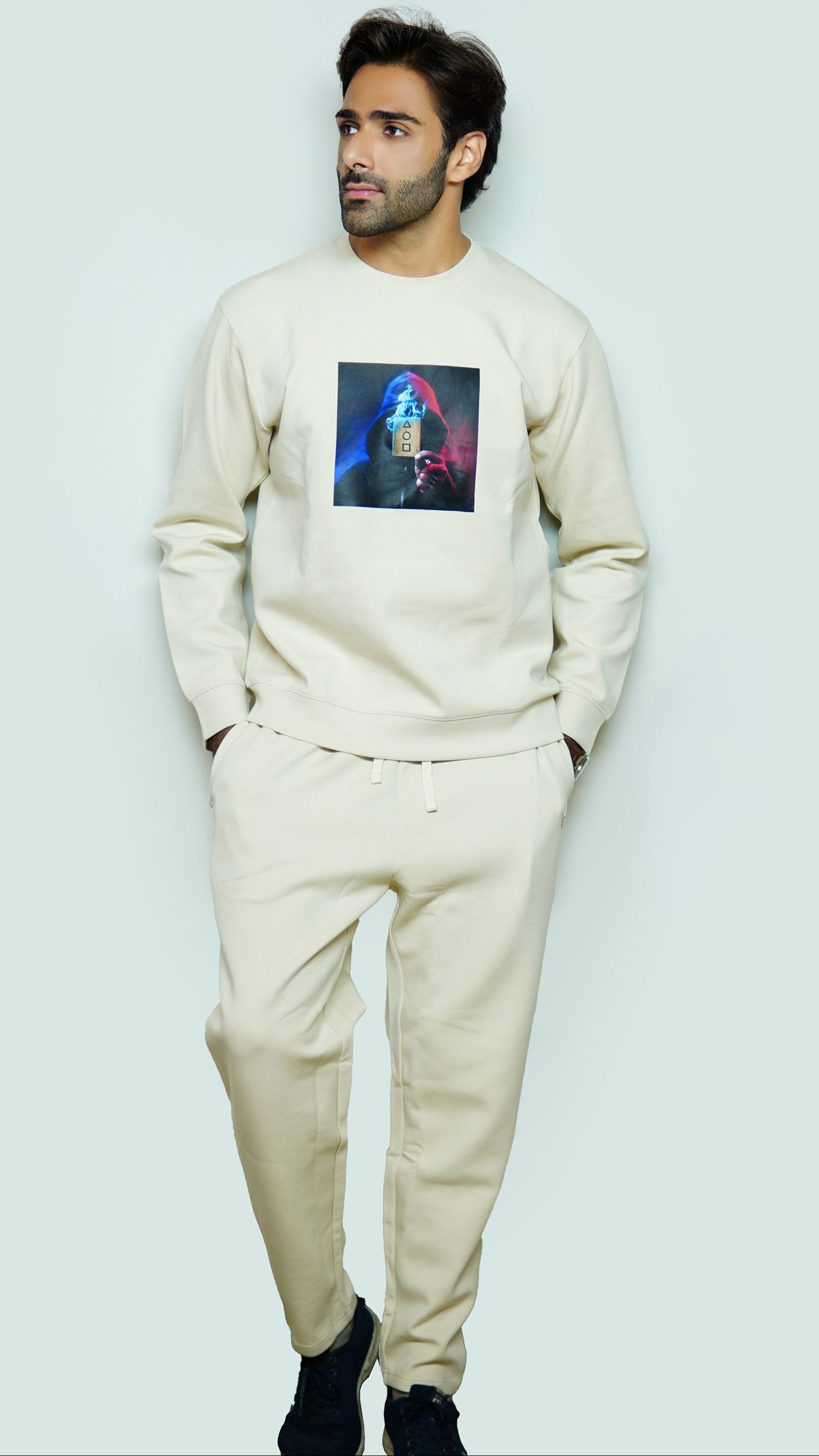Man wearing a beige sweatshirt with a graphic design on a light gray background