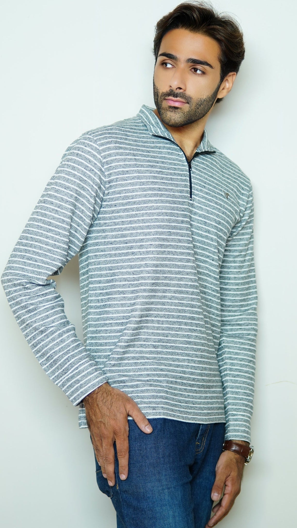 Man wearing a striped long-sleeve shirt and jeans against a white background