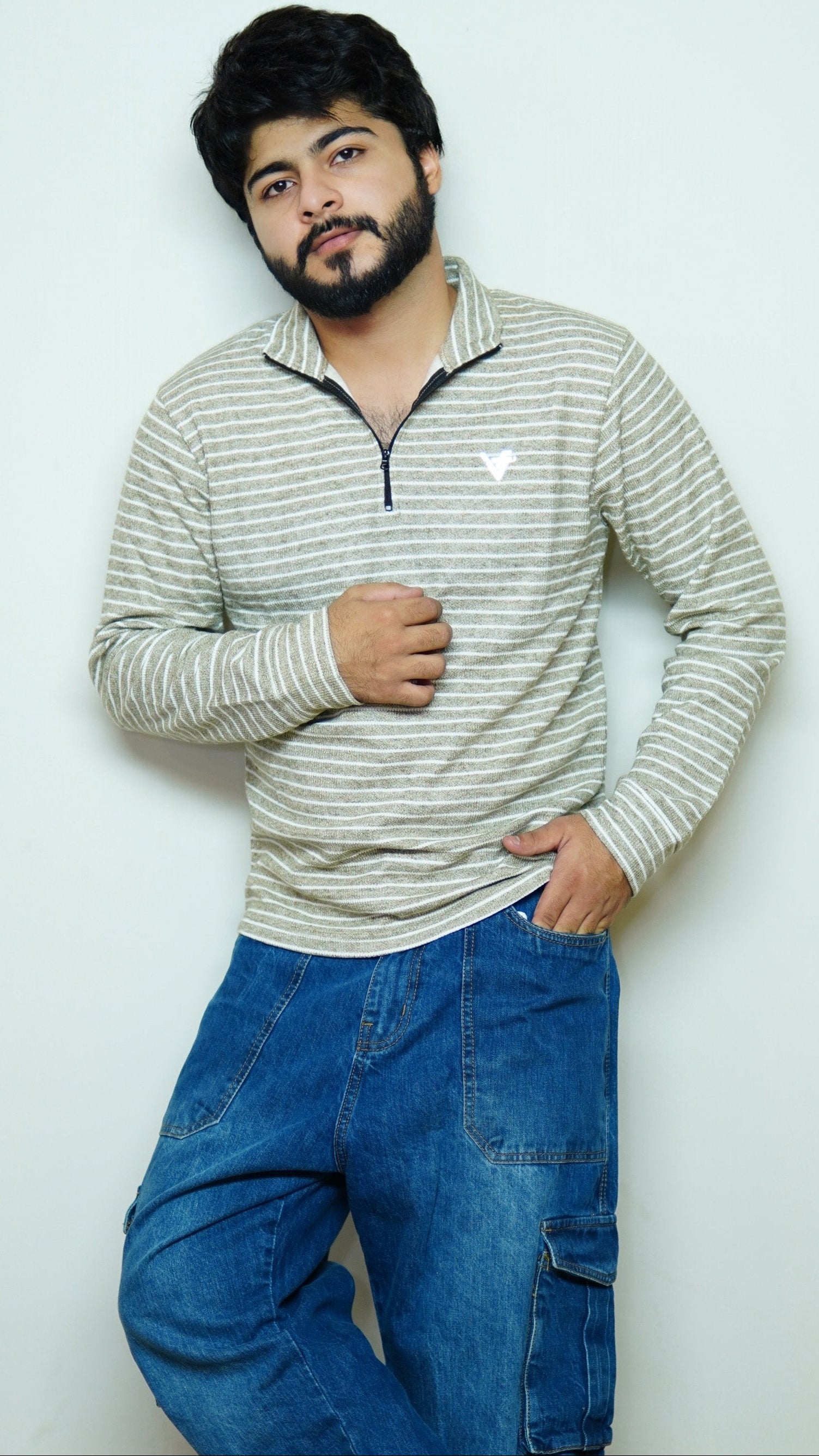 Man wearing a striped sweater and blue jeans against a white background