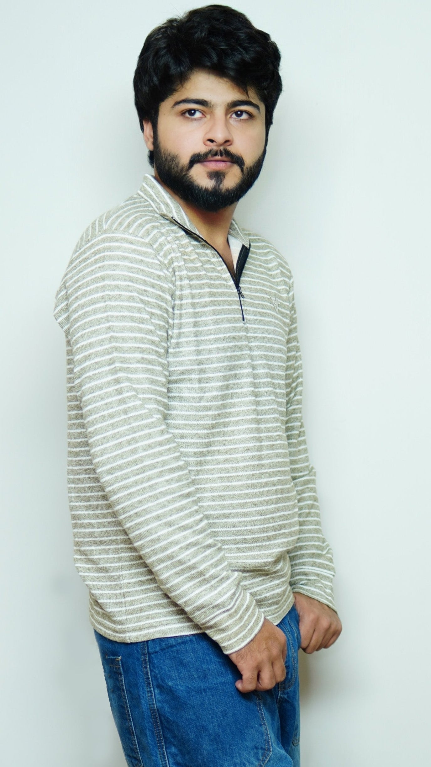 Man wearing a striped sweater and blue jeans against a white background